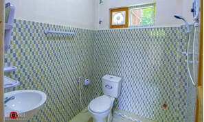 A bathroom with a checkered tile wall, a toilet, a sink, and a shower. - Hein Motel (Meiktila)