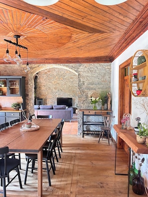 A dining area with a wooden table, chairs, and a stone wall in the background. - Refuge in the countryside (Porto de Mós)