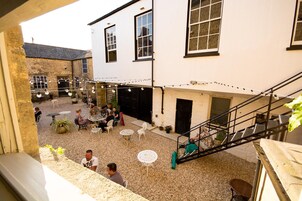 Un patio con mobiliario exterior, una escalera y un edificio con ventanas amplias.