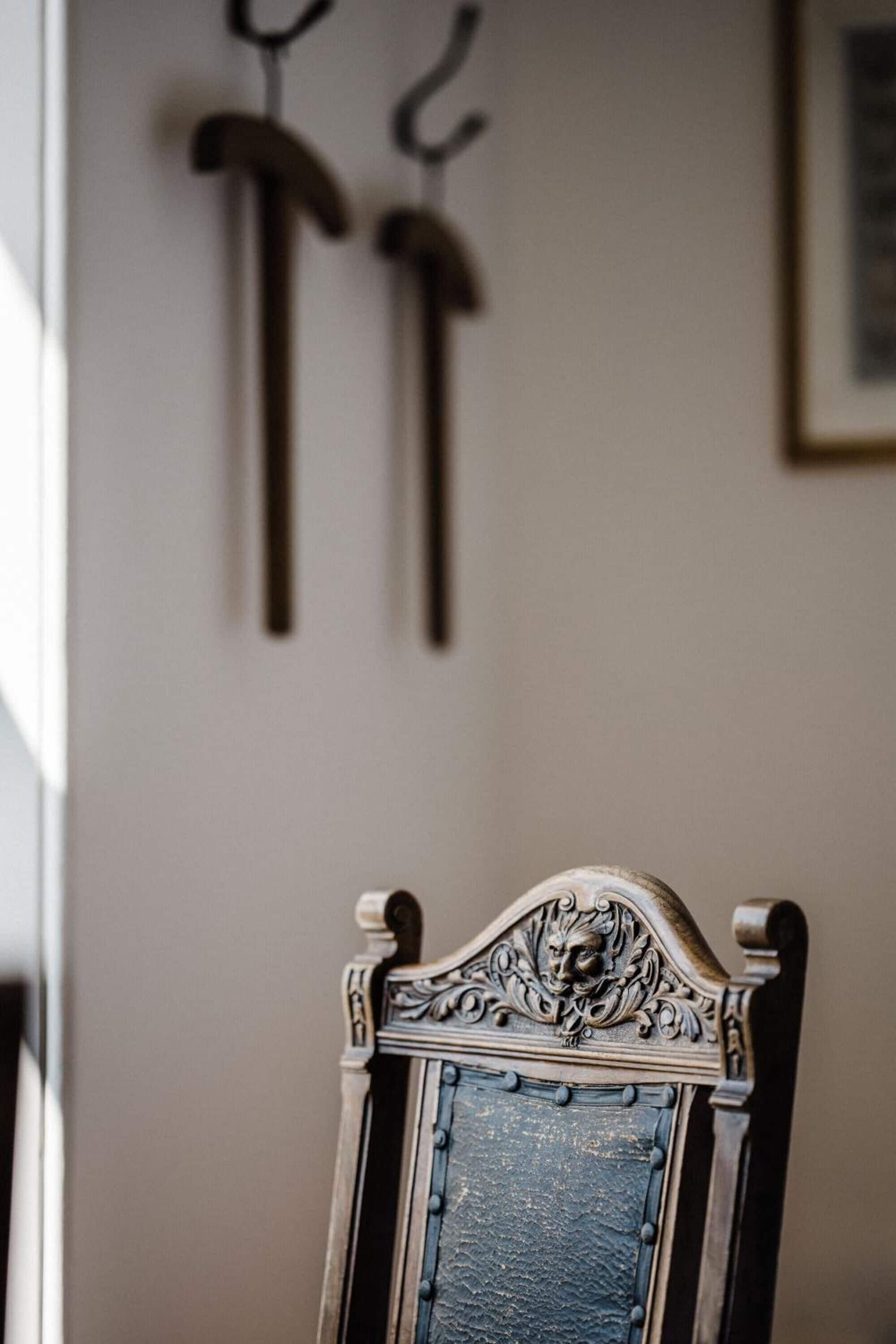A chair with an ornate headrest and a blue cushioned backrest.