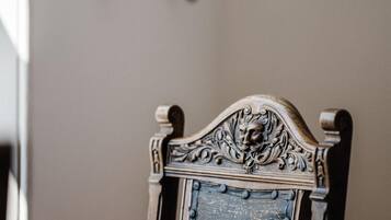 A chair with an ornate headrest and a blue cushioned backrest.