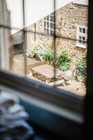 Un edificio de piedra con una mesa de madera y plantas en macetas en un patio.