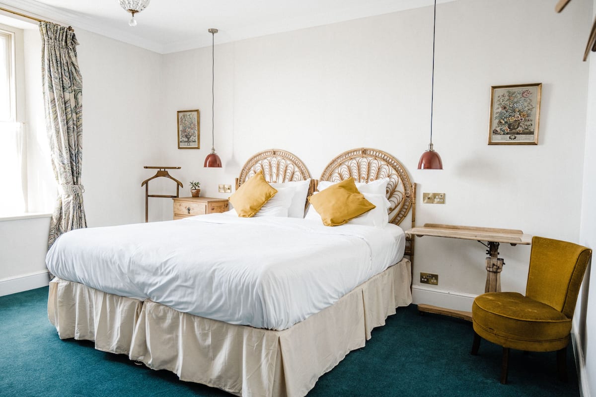 A neatly arranged bedroom with a large bed, bedside tables, a chair, and a desk.