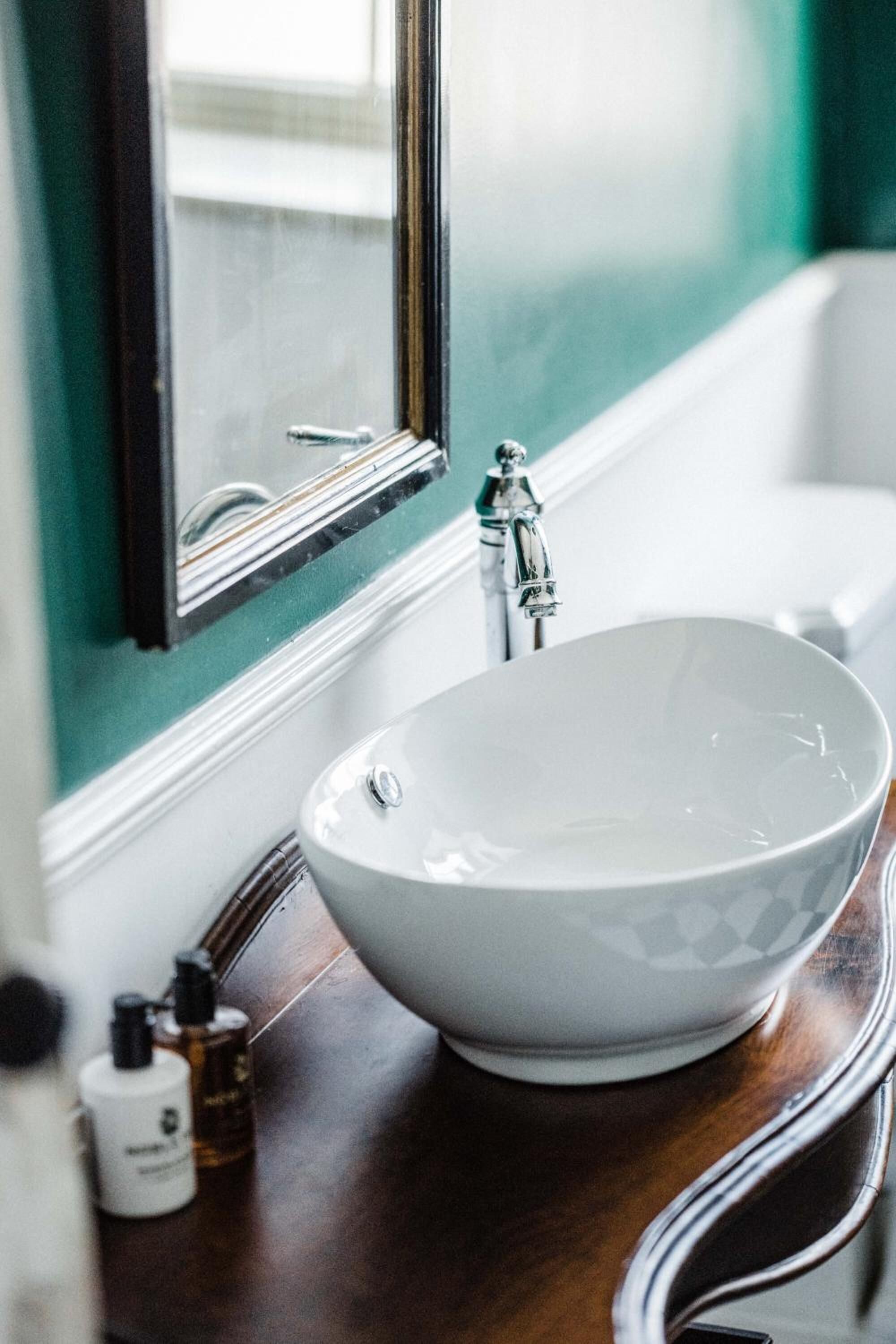 Un baño con un lavamanos blanco tipo recipiente, un espejo y una bañera.