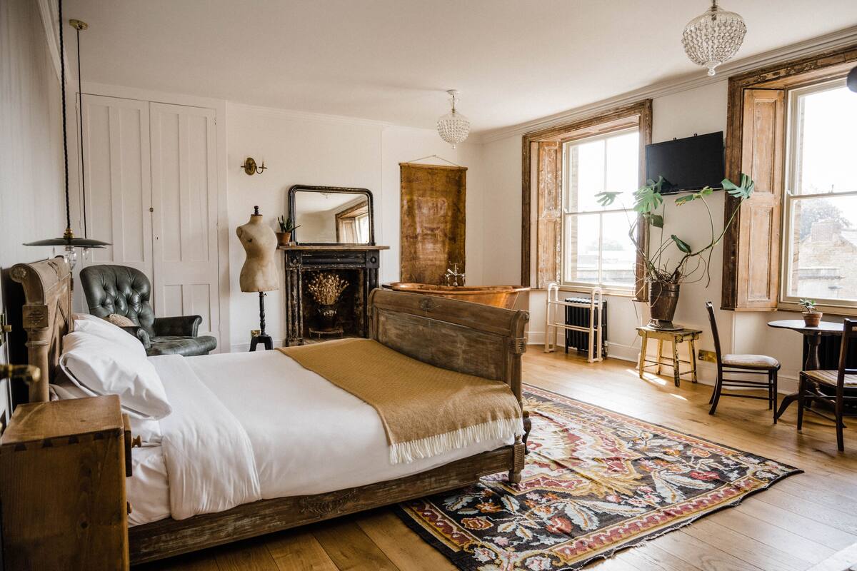 A bedroom with a wooden bed, a large mirror, a dresser, and a television on the wall.