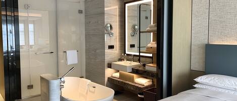 A modern bathroom with a freestanding bathtub, a glass shower enclosure, and a vanity with a mirror.