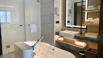 Une salle de bain moderne avec une baignoire sur pieds, un grand miroir et un meuble-lavabo doté d’un évier et d’un porte-serviettes.