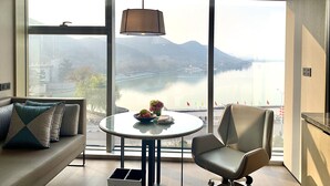 Habitación de hotel moderna con un gran ventanal que ofrece vistas a un río y montañas.