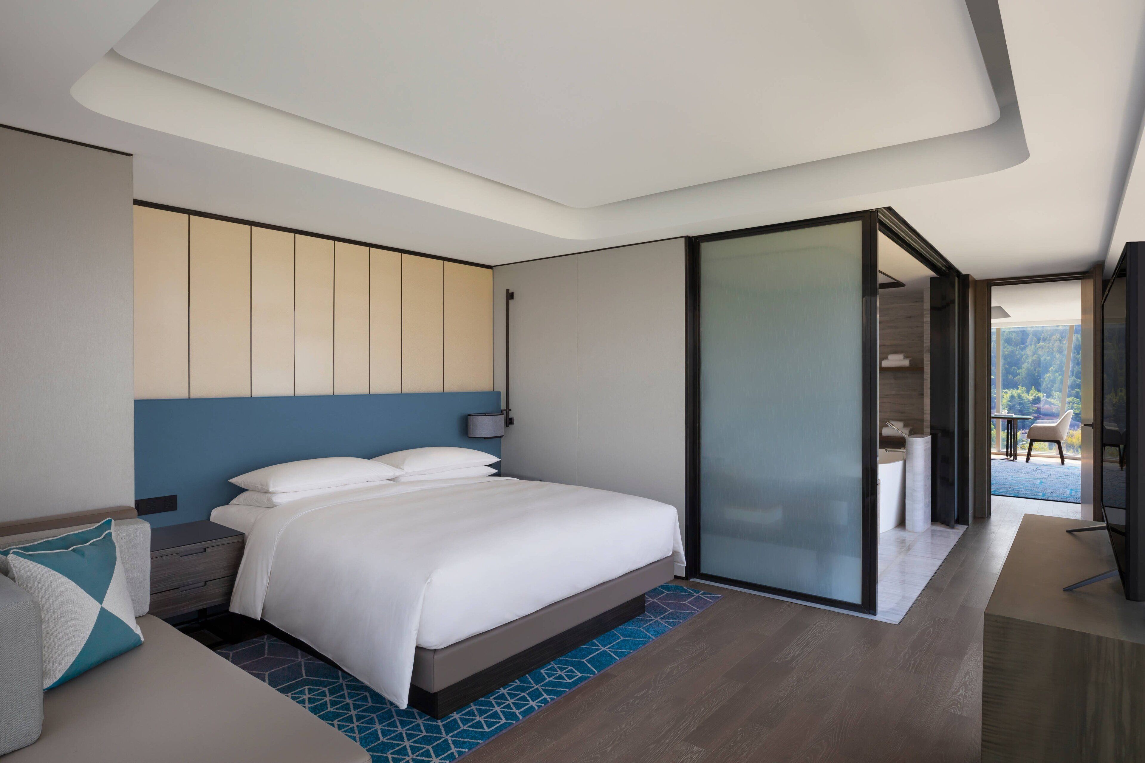 Ett modernt hotellrum med en stor säng, en soffa, ett skrivbord och en balkong med utsikt.