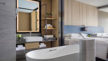 A modern bathroom with a freestanding bathtub, a large mirror, and built-in shelves with toiletries.