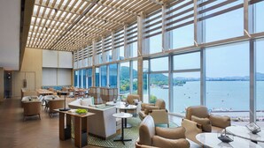 Un amplio salón con ventanas grandes, techo de madera y varias zonas de estar.