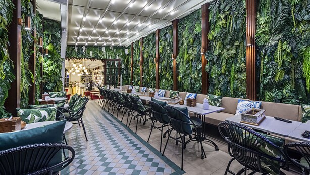 A restaurant with a long counter, multiple seating areas, and a ceiling with a grid of lights.