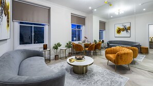 A modern living room with a curved grey sofa, a round coffee table, and a dining area with a table and chairs.