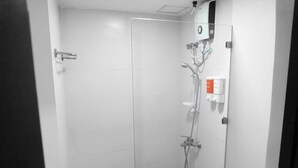 Een moderne douche met een glazen deur, een bedieningspaneel en een handdouche.