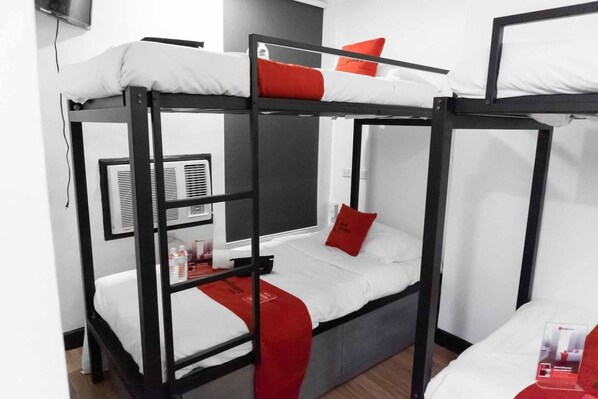 A bunk bed room with a white mattress, red pillows, and a small table with a red cloth.