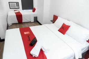 A hotel room with two beds, each with white bedding and red accents. There is a red and white blanket on the bed, and a red pillow with text. - Reddoorz Plus Near Bamboo Organ Las Pinas (Las Pinas)