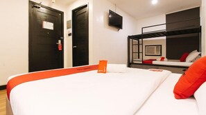 Habitación de hotel con literas, una cama individual con detalles naranja, un televisor montado en la pared y una puerta con manija roja.
