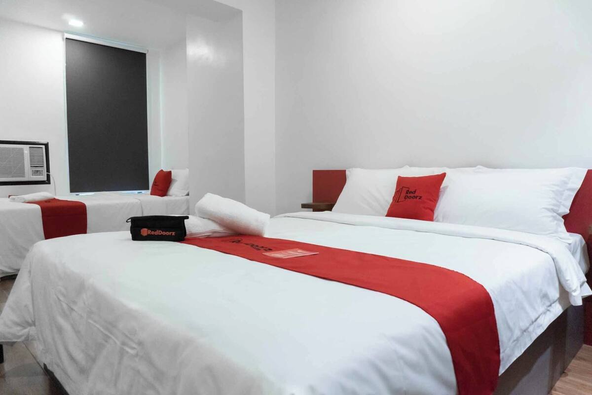 Een hotelkamer met een groot bed, twee kleinere bedden en een bureau.