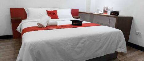 A hotel room with a bed, a nightstand, a desk, and a wardrobe.