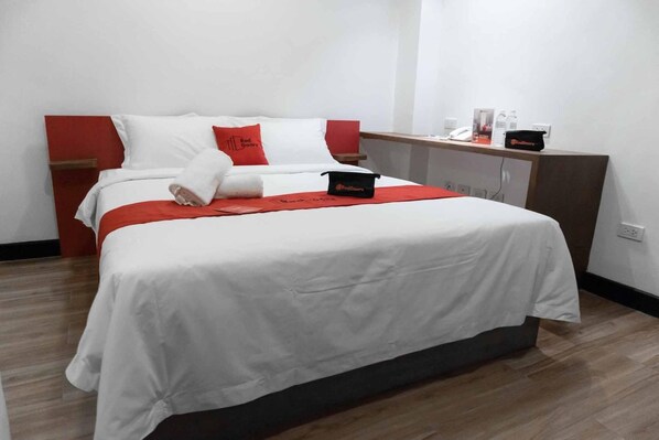 Hotellihuone, jossa on sänky, yöpöytä, työpöytä ja vaatekaappi.
