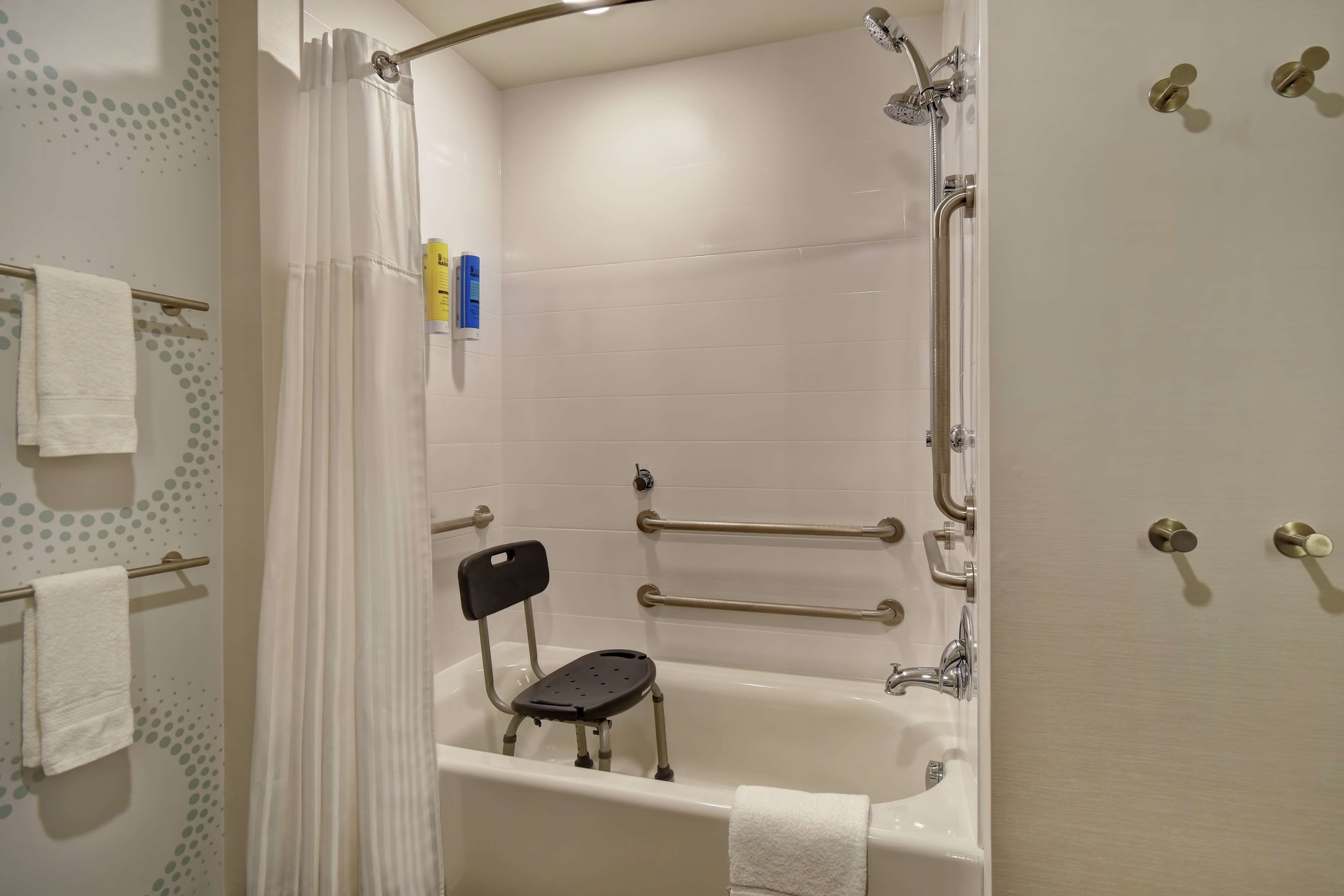 Ein Badezimmer mit Badewanne, Dusche und Haltegriffen.