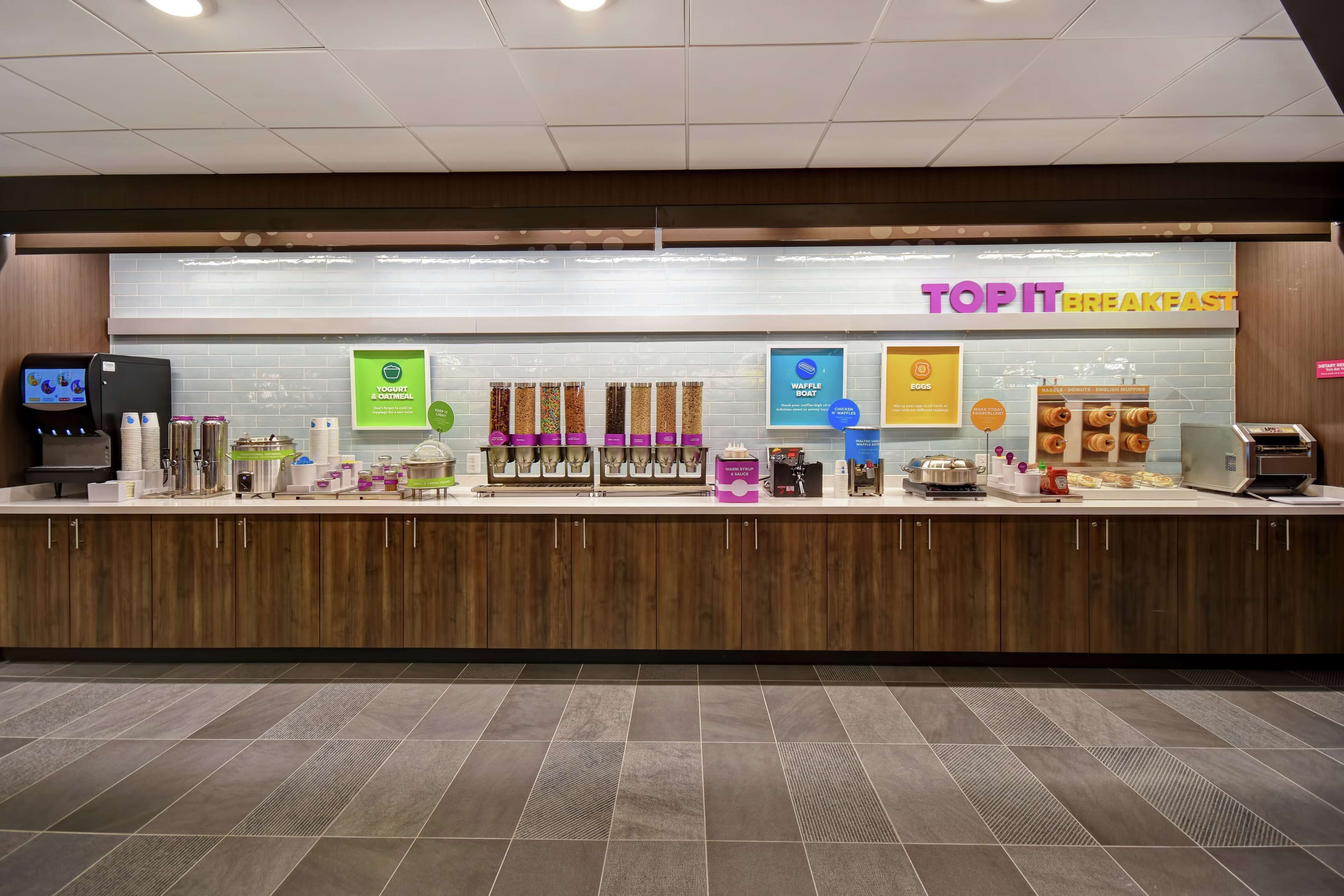 A breakfast counter with various food items and a digital menu display.