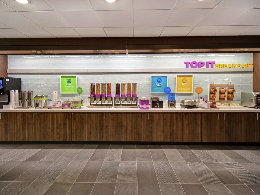 A breakfast counter with various food items and a digital menu display.