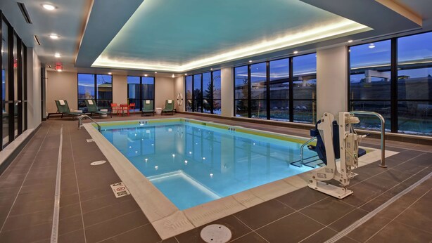 Una piscina interior con agua cristalina y azul, rodeada de amplios ventanales que ofrecen vistas al exterior.