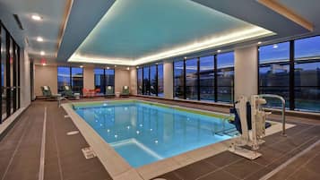 Relax by the pool surrounded by comfortable lounge chairs and a small table.
