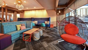 Un área de descanso moderna con un sofá azul, una silla colgante roja y una mesa de madera.