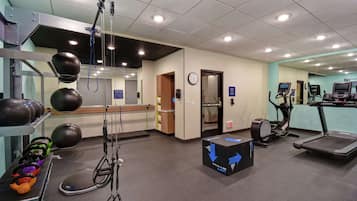 A gym with exercise equipment, a mirror, and a clock on the wall.