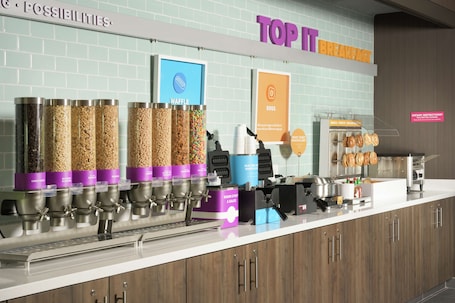 A breakfast station with waffle and waffle syrup dispensers, a sign for dietary restrictions, and a waffle display.