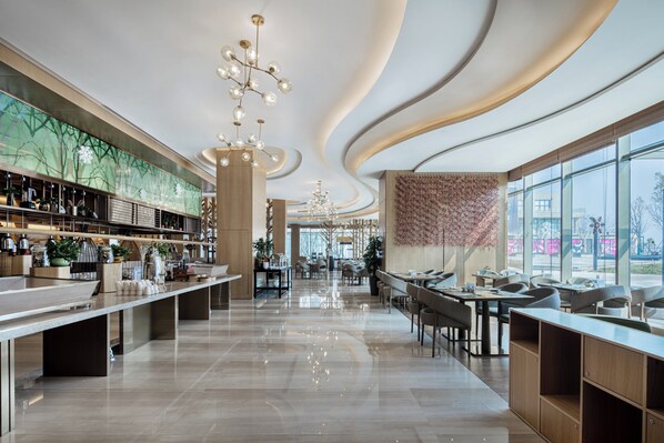 A modern restaurant with a long counter, multiple seating areas, and a large window offering a view of the outside.