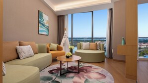 A modern living room with two sofas, a coffee table, and a view of a cityscape through large windows. - Holiday Inn Changsha Dawangshan by IHG (Changsha)