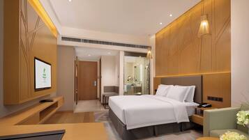 Habitación de hotel moderna con una cama grande, televisión, escritorio y baño visible a través de una puerta abierta.