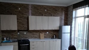 A kitchen with wooden flooring, white cabinets, a stove, and a dining table with chairs.