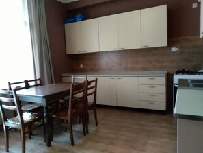 A compact kitchen with white cabinets, a dining table with chairs, and a stove.