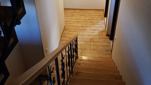 A wooden staircase with a metal railing, leading to a landing with a door.