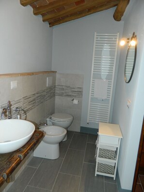 A bathroom with a wooden vanity, a sink, a toilet, and a shower with a glass door.