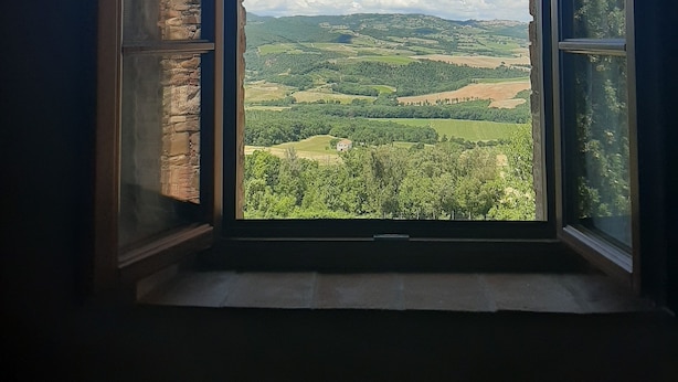 Una ventana con vistas a un paisaje verde y montañas distantes.