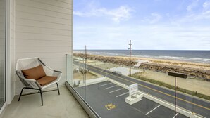 A balcony with a wicker chair, a view of the beach, and a fire lane sign.