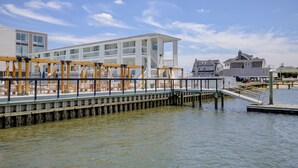 A waterfront property with a wooden deck, white building, and dock extending into the water.