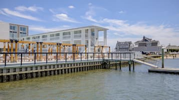 A waterfront property with a wooden deck, white building, and dock extending into the water.