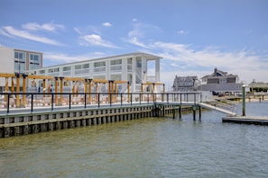 A waterfront property with a wooden deck, white building, and dock extending into the water.