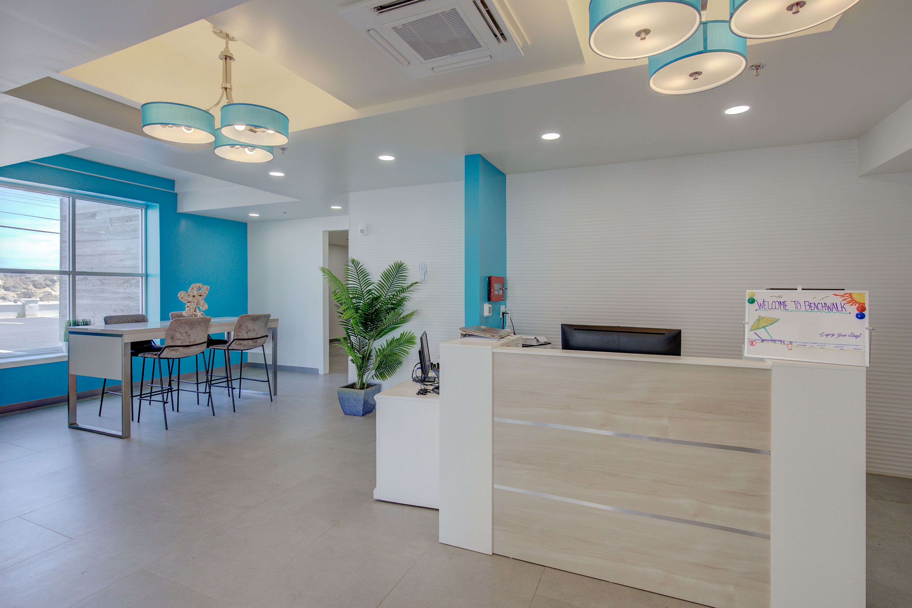 A reception area with a desk, chairs, a potted plant, and a sign.