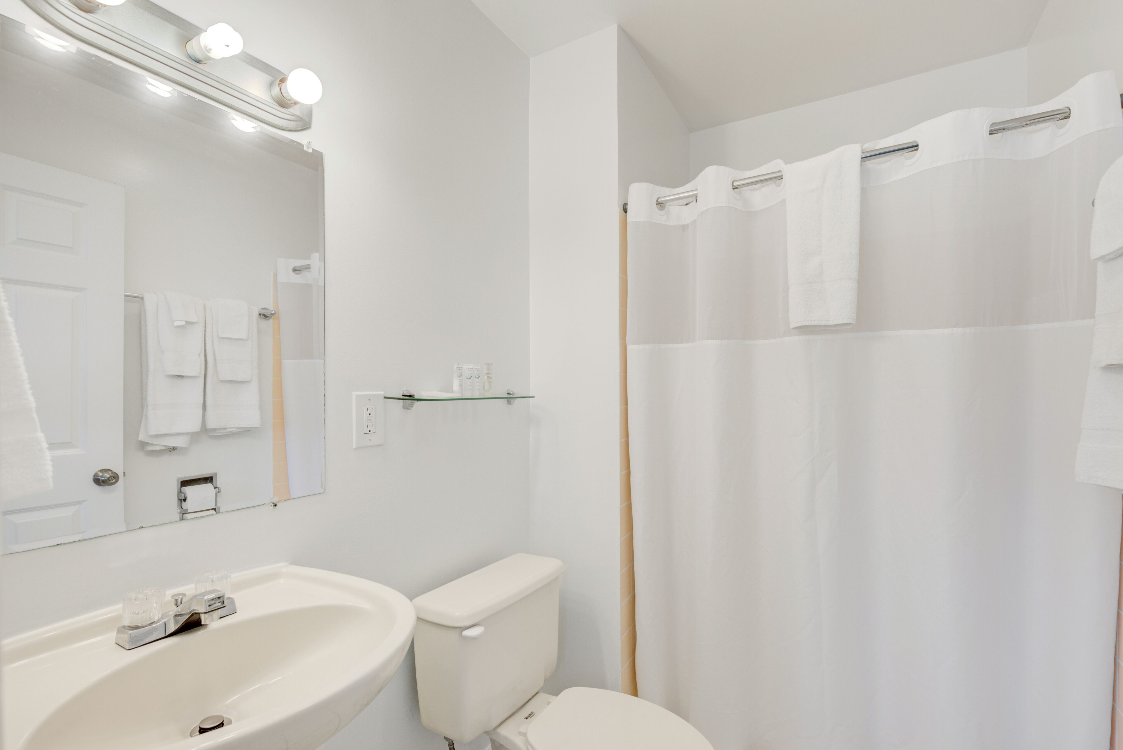 A bathroom with a sink, mirror, and shower curtain.