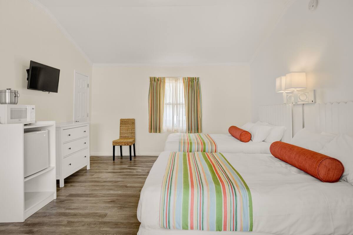A hotel room with a bed, a chair, a desk with a television, and a microwave.