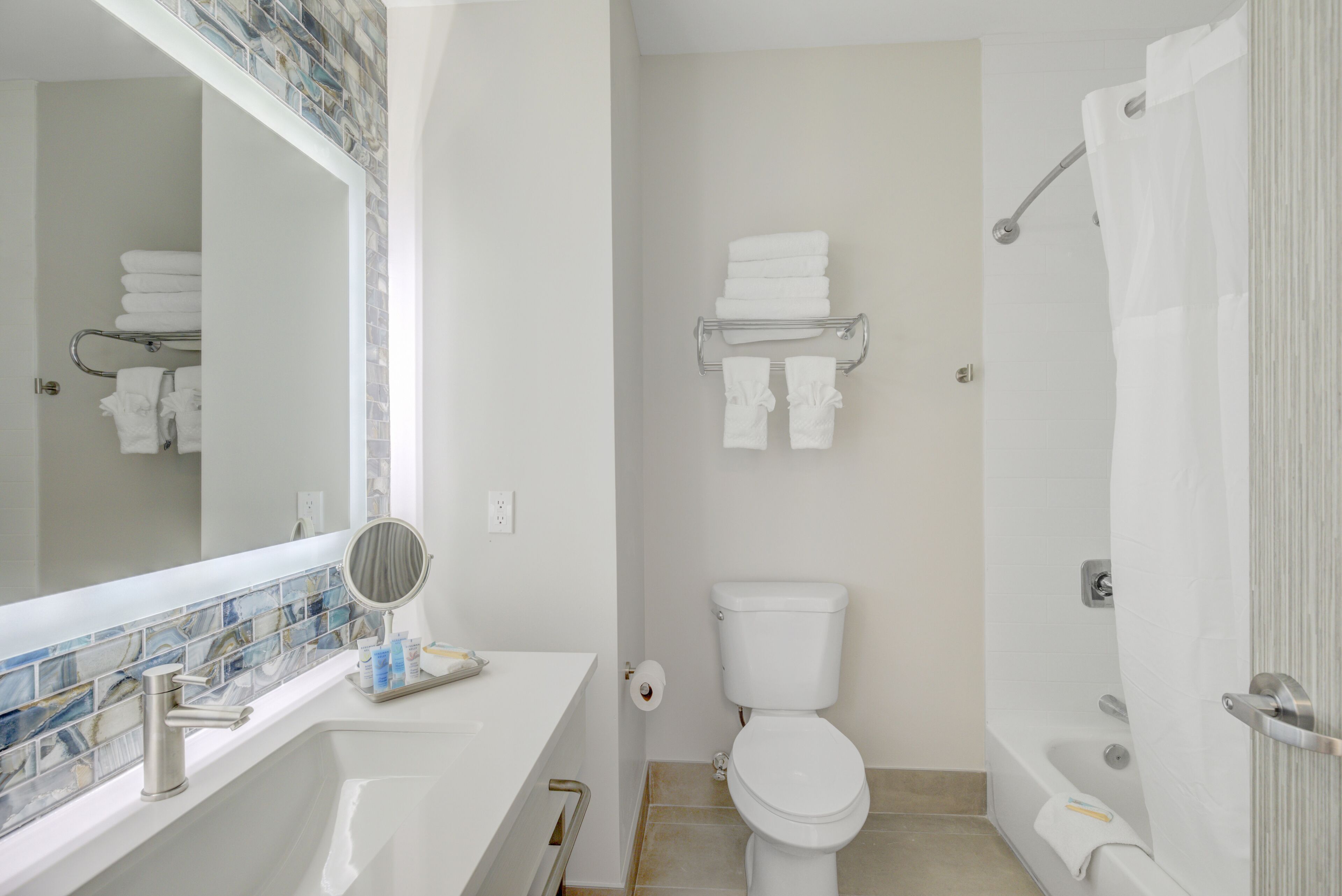 A bathroom with a white sink, a mirror, a toilet, and a shower.