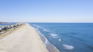 Una playa costera con orilla arenosa y una hilera de casas a la orilla del agua.