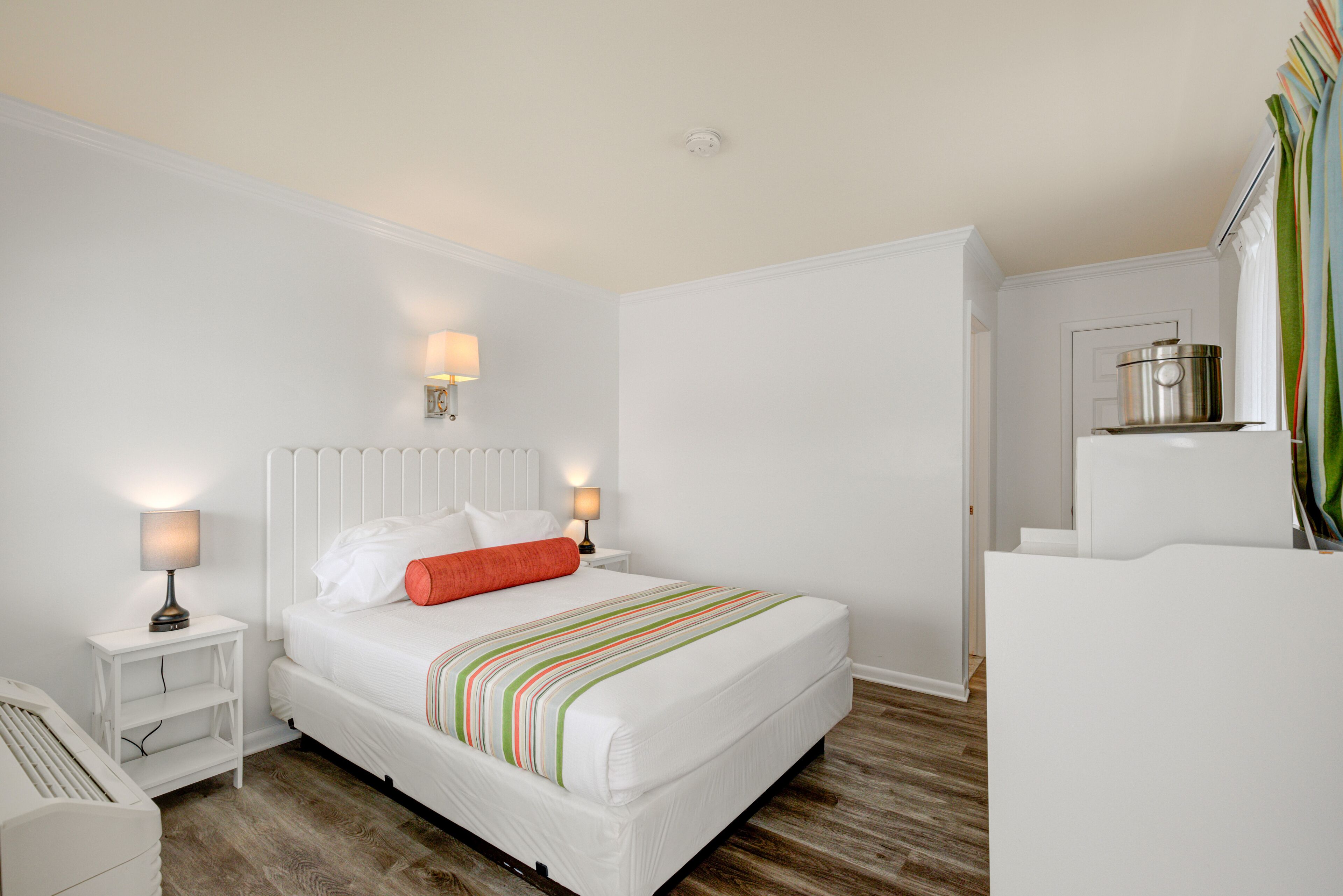 Une chambre à coucher bien rangée, avec un lit, des tables de chevet et une petite table de nuit.